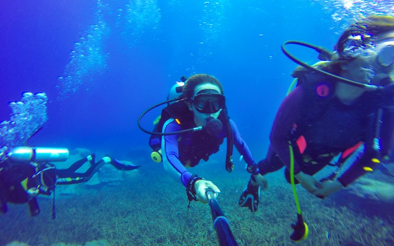 Underwater couple scuba diving selfie shot with selfie stick. De