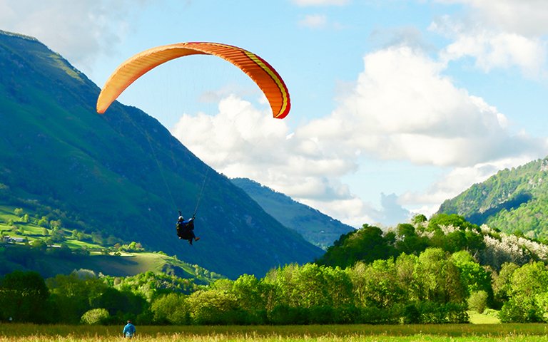 Paraglider tandem landing on the field between mountains in brig